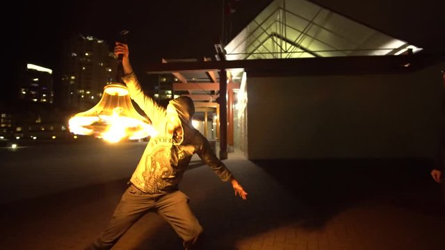 Orbiting shot of man spinning unusual fire prop