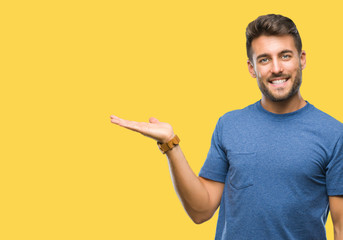 Young handsome man over isolated background smiling cheerful presenting and pointing with palm of hand looking at the camera.