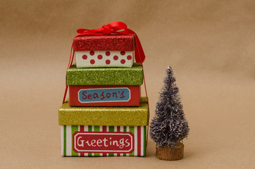 Little colorful Christmas presents beside a little Christmas tree on brown background. Christmas decoration 