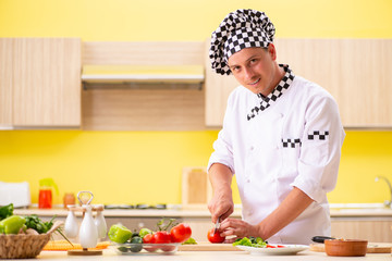 Obraz na płótnie Canvas Young professional cook preparing salad at kitchen