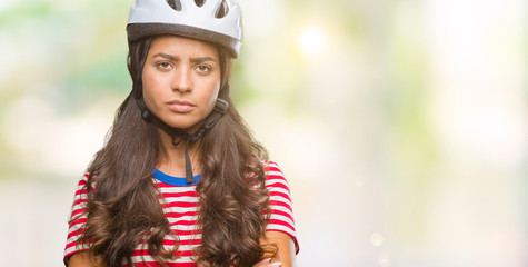 Young arab cyclist woman wearing safety helmet over isolated background skeptic and nervous, disapproving expression on face with crossed arms. Negative person.