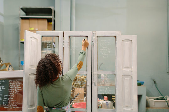Employee in shop writing on glass
