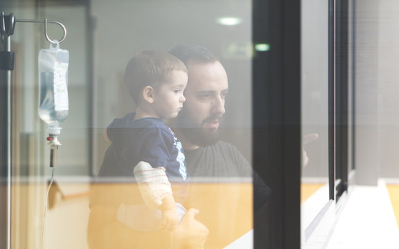 Father holding his son in arms looking through the window - Powered by Adobe
