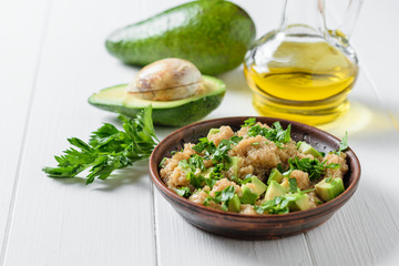Salad of amaranth seeds, avocado and parsley with olive oil on a white wooden table.