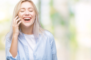 Young blonde woman talking using smarpthone over isolated background with a happy face standing and smiling with a confident smile showing teeth
