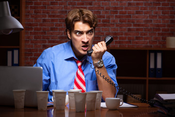 Young employee drinking coffee working at night shift 