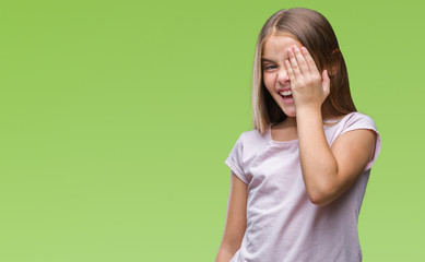 Young beautiful girl over isolated background covering one eye with hand with confident smile on face and surprise emotion.