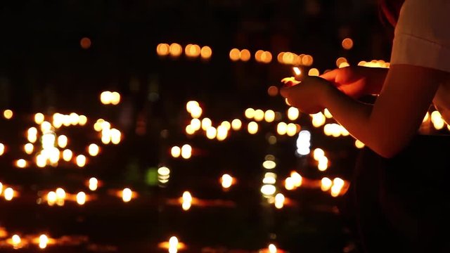 Closeup shot of woman's hand putting a floating candle into the water.