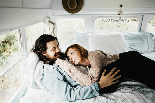 Cute hipster couple cuddling in converted school bus tiny home