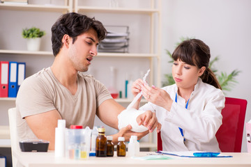 Fototapeta premium Young man with bandaged arm visiting female doctor traumatologis