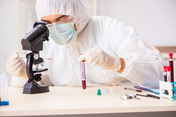 Young handsome lab assistant testing blood samples in hospital 