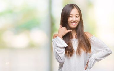 Young asian woman over isolated background smiling doing phone gesture with hand and fingers like talking on the telephone. Communicating concepts.