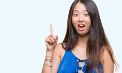 Young asian woman over isolated background pointing finger up with successful idea. Exited and happy. Number one.
