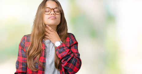 Young beautiful brunette woman wearing jacket and glasses over isolated background Touching painful neck, sore throat for flu, clod and infection