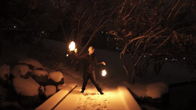 Slowmotion shot of man spinning poi in snowy woods