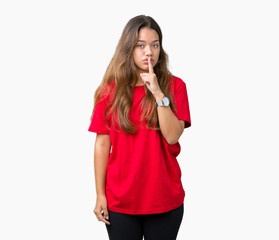 Young beautiful brunette woman wearing red t-shirt over isolated background asking to be quiet with finger on lips. Silence and secret concept.