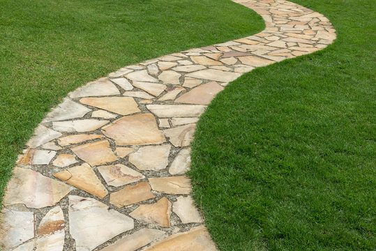 Stone path on green grass in the garden