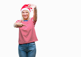 Young beautiful blonde woman wearing christmas hat over isolated background smiling making frame with hands and fingers with happy face. Creativity and photography concept.