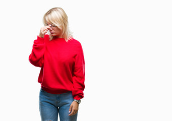 Young beautiful blonde woman wearing sweater and glasses over isolated background tired rubbing nose and eyes feeling fatigue and headache. Stress and frustration concept.