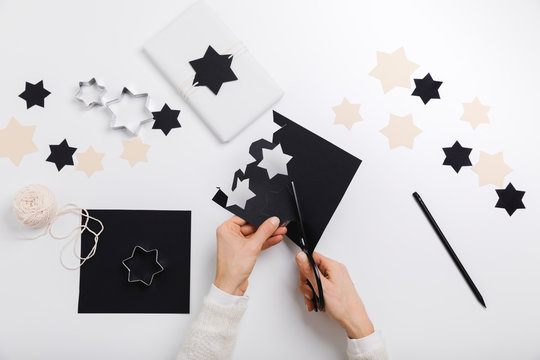 Female hands cut star-shaped cards to make gift package