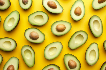 Exotic halved avocados on yellow background.