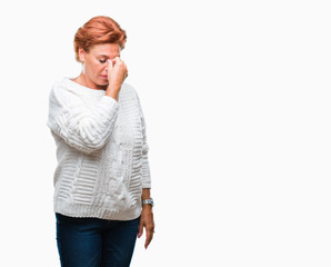 Atrractive senior caucasian redhead woman wearing winter sweater over isolated background tired rubbing nose and eyes feeling fatigue and headache. Stress and frustration concept.