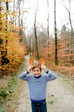 little boy outside in the fall playing with leaves