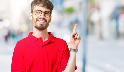 Young handsome man wearing glasses over isolated background with a big smile on face, pointing with hand and finger to the side looking at the camera.