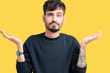 Young handsome man over isolated background clueless and confused expression with arms and hands...