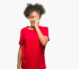 Fototapeta na wymiar Young afro american woman over isolated background covering one eye with hand with confident smile on face and surprise emotion.