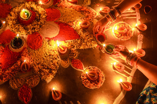 Woman enlightening Diya in Rangoli at Diwali Celebration