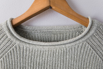 Light green sweater hanging on grey wall