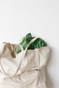 a linen bag full of green leafy vegetables 