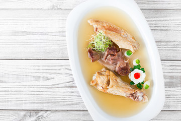 Homemade jelly chicken decorated with greens and eggs on plate on wooden background close up. Cold Meat Dishes