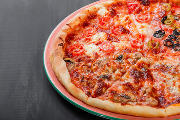 Mixed pizza Italian food with chicken, tomatoes, mushrooms, ham, salami, olive and cheese on dark wooden background. Homemade pizza.