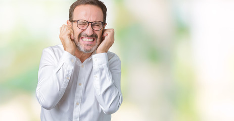 Handsome middle age elegant senior business man wearing glasses over isolated background covering ears with fingers with annoyed expression for the noise of loud music. Deaf concept.