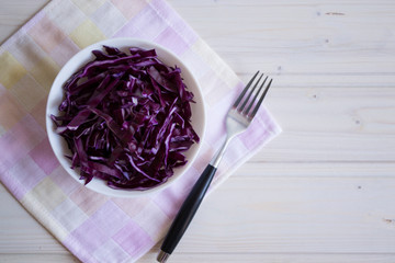 Photo salad of chopped purple cabbage in a plate on a napkin on a light background.