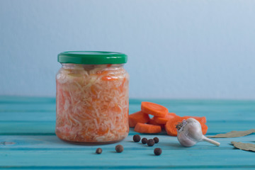 Photos of sauerkraut in a jar and garlic and bay leaves on a bright blue background.
