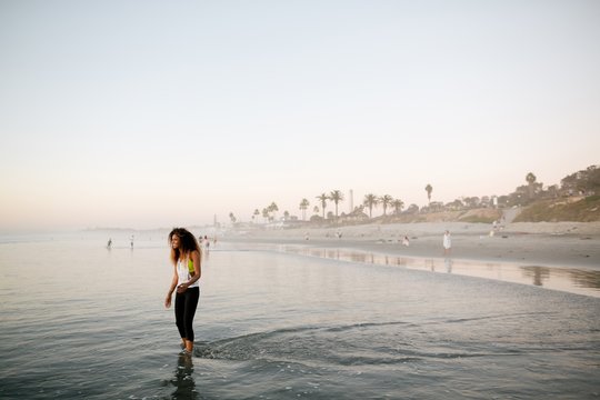 Fit, stylish woman enjoying sunset walk in ocean water
