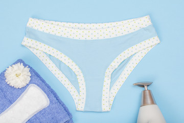 Beautiful women's panties with a sanitary napkin and towel on blue background.