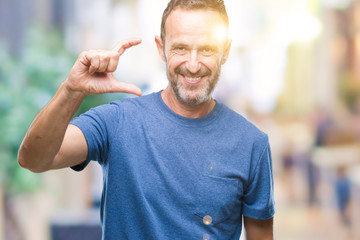 Middle age hoary senior man over isolated background smiling and confident gesturing with hand doing size sign with fingers while looking and the camera. Measure concept.