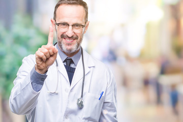 Middle age senior hoary doctor man wearing medical uniform isolated background showing and pointing up with finger number one while smiling confident and happy.