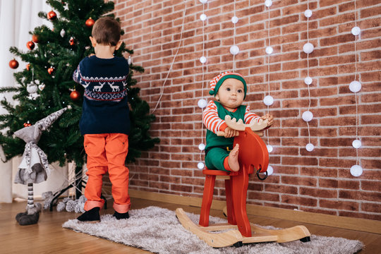 Lovely baby riding a deer while older brother decoration a Chris
