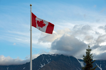 The Canadian Flag flying over mountain peaks