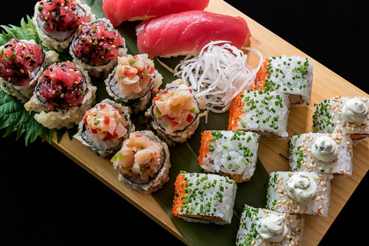 Sushi and sashimi served on nicely decorated wooden plate.