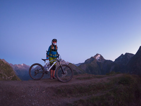 Woman with mtb in staggering alpine landscape during twilight