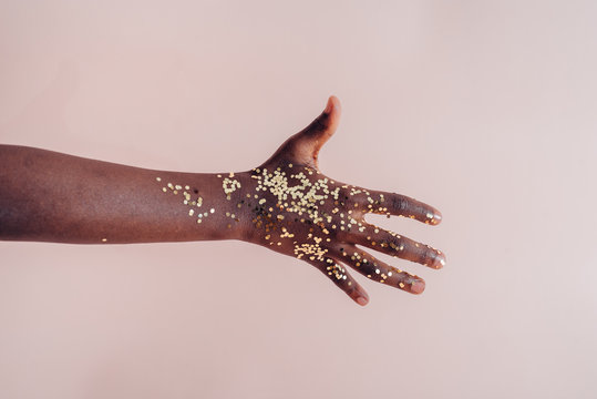 Black girl's hand with golden confetti