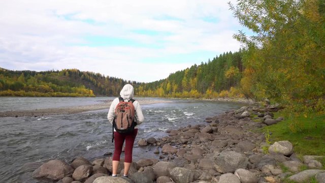 Altai. The woman the traveler costs on the bank of the mountain river. Two videos in one.