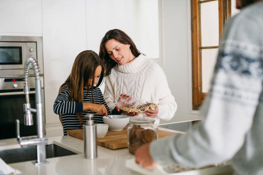 Mother and her daughter preparing healthy breakfast in the kitchen.
