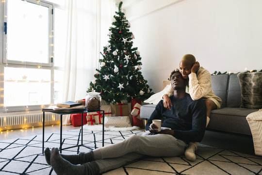 Young Multiethnic Couple Relaxed At Home On Christmas.